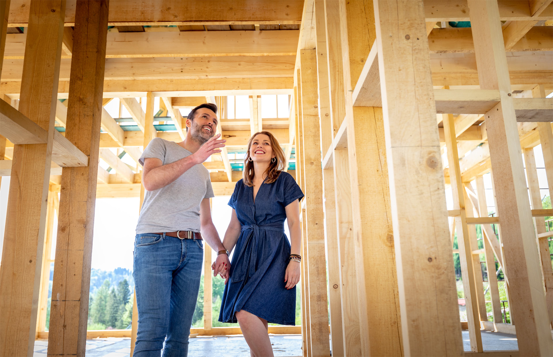 Happy couple holding hands inside the wood framing of their new UBuildIt custom home