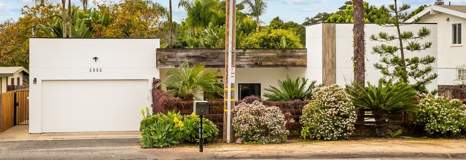 Modern white stucco exterior with palm trees and lush landscaping, the Valley Home, a custom home built by a UBuildIt San Diego owner-builder client in Carlsbad, CA
